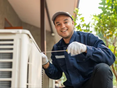 A service technician smiles while repairing the HVAC