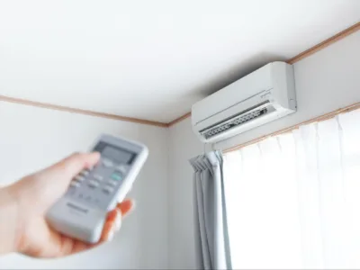 A person's hand is seen pointing a remote at an AC system
